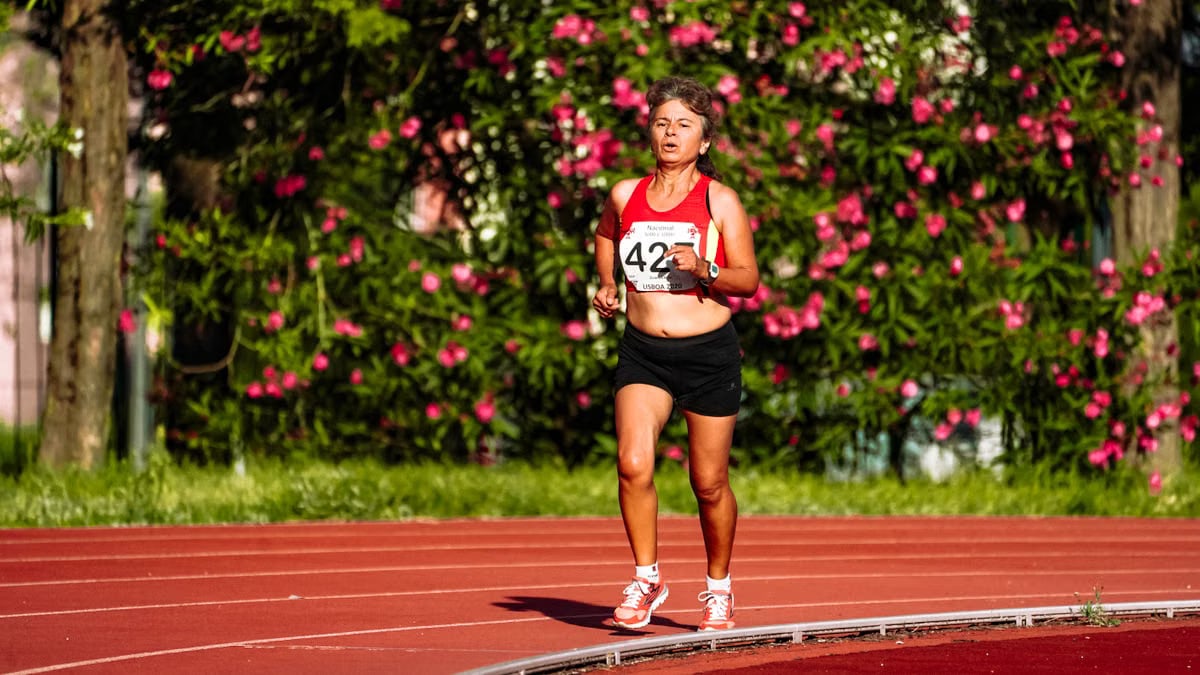 Middle aged female athlete in sportswear running during track and field competition while looking forward